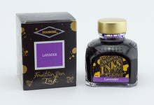 Load image into Gallery viewer, A glass bottle of 80ml Diamine Lavender fountain pen ink next to its packaging box, in front of a white background.
