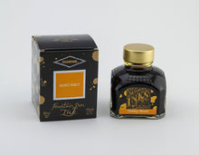 Load image into Gallery viewer, A glass bottle of 80ml Diamine Honey Burst fountain pen ink next to its packaging box, in front of a white background.
