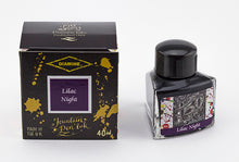 Load image into Gallery viewer, A glass bottle of 40ml Diamine 150th Anniversary Lilac Night fountain pen ink next to packaging box, in front of a white background.
