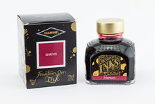 Load image into Gallery viewer, A glass bottle of 80ml Diamine Maroon fountain pen ink next to its packaging box, in front of a white background.
