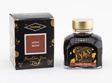 Load image into Gallery viewer, A glass bottle of 80ml Diamine Saddle Brown fountain pen ink next to its packaging box, in front of a white background.
