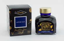 Load image into Gallery viewer, A glass bottle of 80ml Diamine Sapphire Blue fountain pen ink next to its packaging box, in front of a white background.
