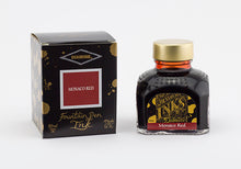 Load image into Gallery viewer, A glass bottle of 80ml Diamine Monaco Red fountain pen ink next to its packaging box, in front of a white background.
