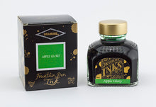 Load image into Gallery viewer, A glass bottle of 80ml Diamine Apple Glory fountain pen ink next to its packaging box, in front of a white background.

