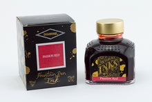 Load image into Gallery viewer, A glass bottle of 80ml Diamine Passion Red fountain pen ink next to its packaging box, in front of a white background.
