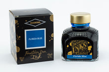 Load image into Gallery viewer, A glass bottle of 80ml Diamine Florida Blue fountain pen ink next to its packaging box, in front of a white background.
