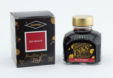 Load image into Gallery viewer, A glass bottle of 80ml Diamine Red Dragon fountain pen ink next to its packaging box, in front of a white background.

